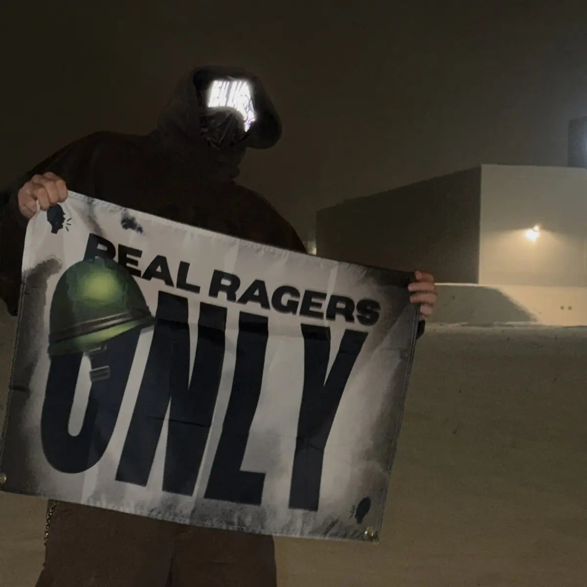 Rager mit Maske hält die weiße RRO-Flagge nachts hoch